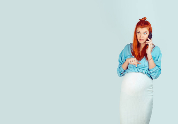 Young redhead girl expecting baby and having phone call looking away in worries confused isolated on light blue background. Unhappy calling her husband - Φωτογραφία, εικόνα