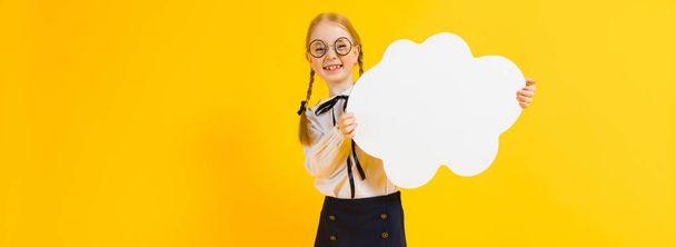 Meisje met rode pigtails op een gele achtergrond. Een charmante meisje in ronde transparante glazen houdt een witte wolk in haar handen. - Foto, afbeelding