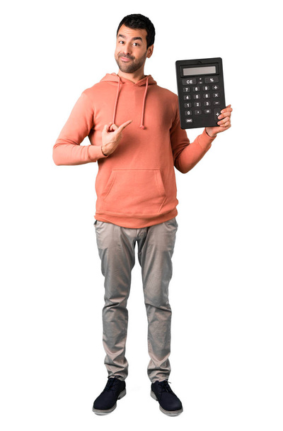 Corpo inteiro de Homem em uma camisola rosa pegando uma grande calculadora e apontando-a com o dedo enquanto sorri. Contagem de máquina em fundo branco isolado
 - Foto, Imagem