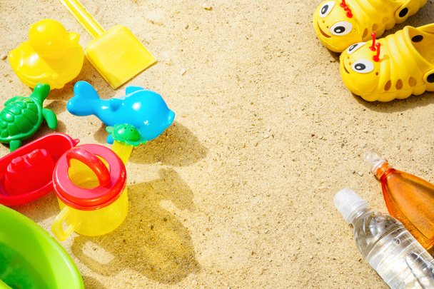 Strand Sommer Sonne Sand Kinder Spielzeug und Flasche Wasser Hausschuhe und Sonnencreme Konzept der Kinder Freizeit Tourismus Unterhaltung Spiele Hautschutz spf uva uvb Strahlensicherheit vor Melanom-Krebs. - Foto, Bild
