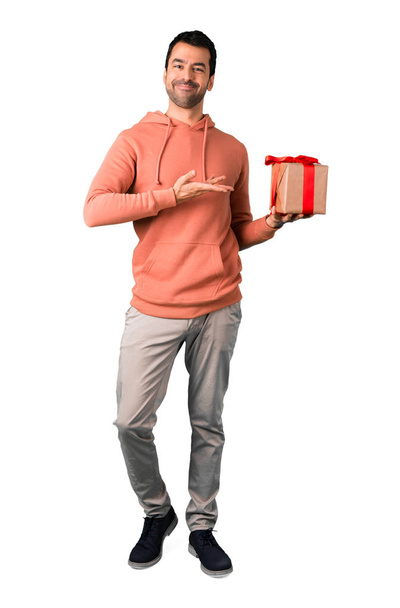 Full body of Man in a pink sweatshirt holding gift boxes in hands on isolated white background - Foto, afbeelding