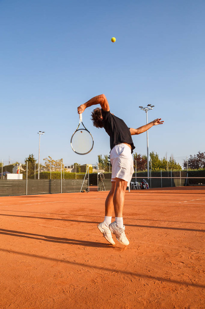 Profesjonalny gracz robi rzut tenisa na korcie w godzinach popołudniowych. - Zdjęcie, obraz