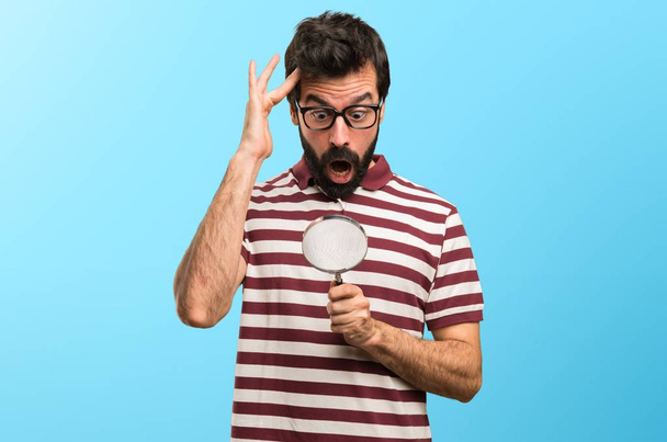 Man with glasses with magnifying glass on colorful background - Фото, зображення