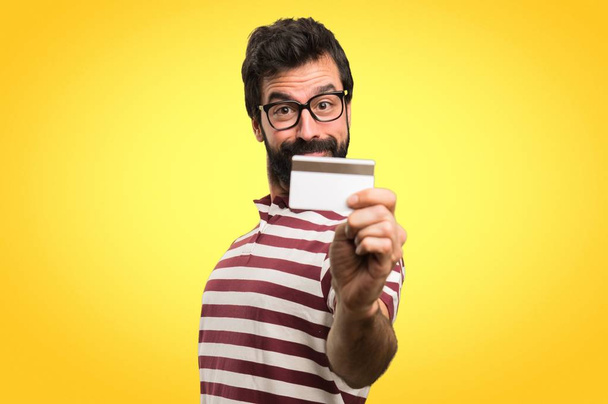 Homem com óculos segurando um cartão de crédito em fundo colorido
 - Foto, Imagem