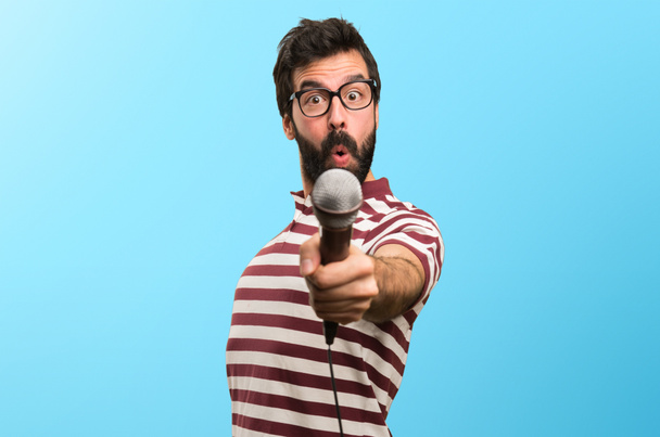 Άνδρας με γυαλιά που τραγουδά με το μικρόφωνο στο πολύχρωμο φόντο - Φωτογραφία, εικόνα