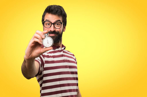 Mann mit Brille hält Jahrgangs-Chronometer auf buntem Hintergrund - Foto, Bild
