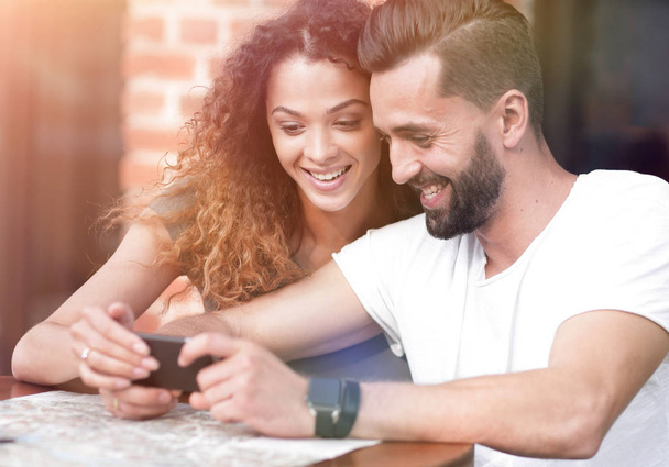 Happy loving  couple using a smartphone sitting in terrace - Фото, зображення