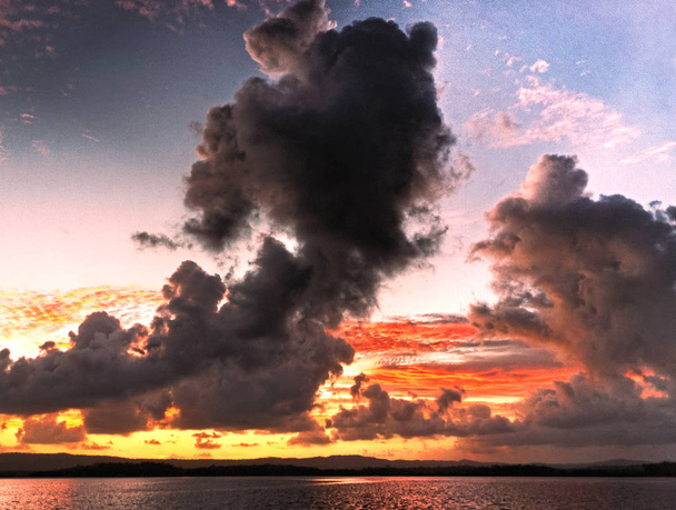 Bir bulut siluetleri okyanus su yansımaları ile featuring kömür ve kırmızı renkli bulutlu tropik gündoğumu deniz manzarası tehdit canlı dikkat çekici. Queensland, Avustralya. - Fotoğraf, Görsel