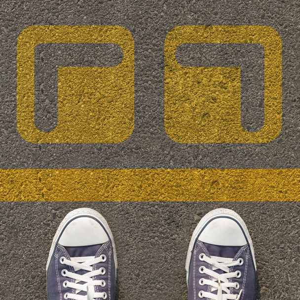 Par de zapatos de pie en una carretera con flecha amarilla de dos vías
 - Foto, imagen