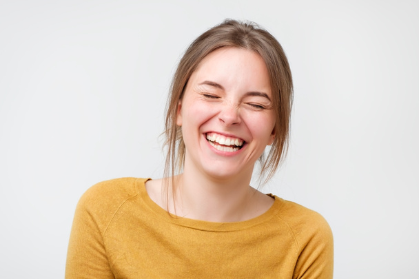 Mooie jonge vrouw in de gele trui lachen - Foto, afbeelding