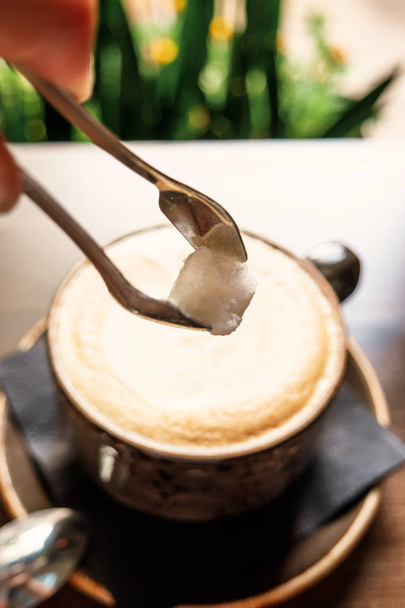 Добавить сахар в чашку горячего кофе латте на деревянный стол
 - Фото, изображение