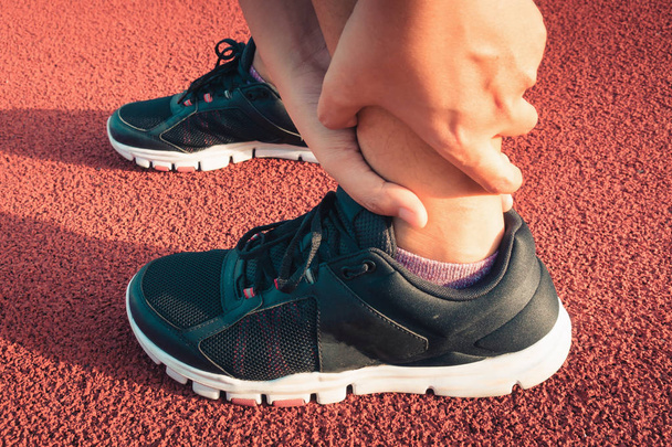 Close up portrait of sporty woman having ankle injury in running track., Healthcare and sport concept. - Foto, Bild