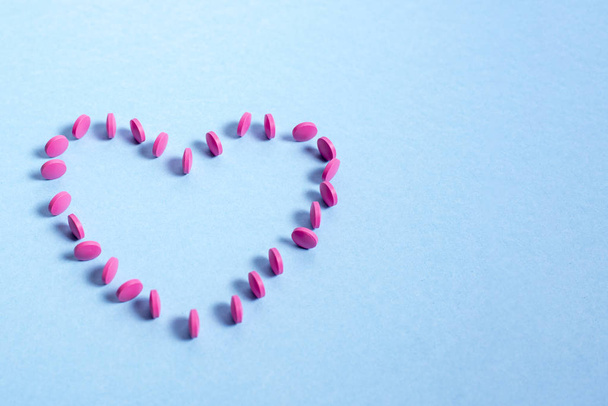 Pink round tablets spread out in the shape of  heart  - Fotografie, Obrázek