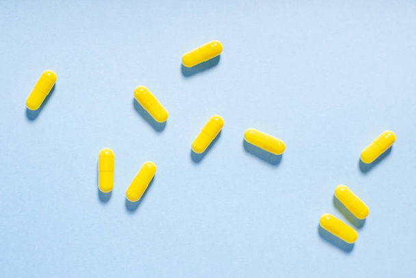 Gele capsules op blauw - Foto, afbeelding