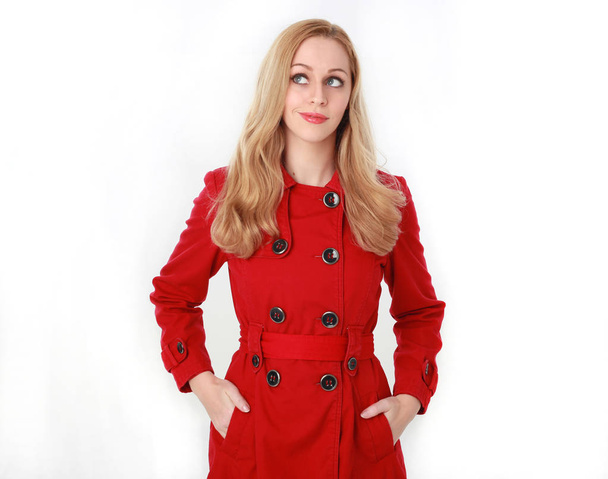 Portret van vrij blond meisje dragen rode regenjas. geïsoleerd op witte studio achtergrond. - Foto, afbeelding