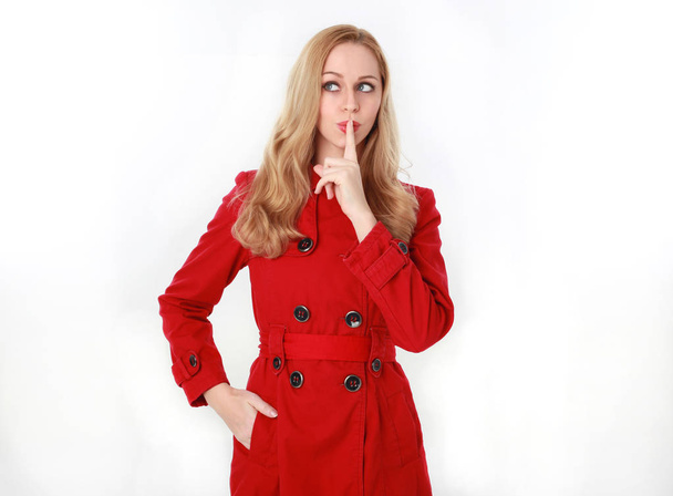 Porträt eines hübschen blonden Mädchens im roten Trenchcoat. isoliert auf weißem Studiohintergrund. - Foto, Bild