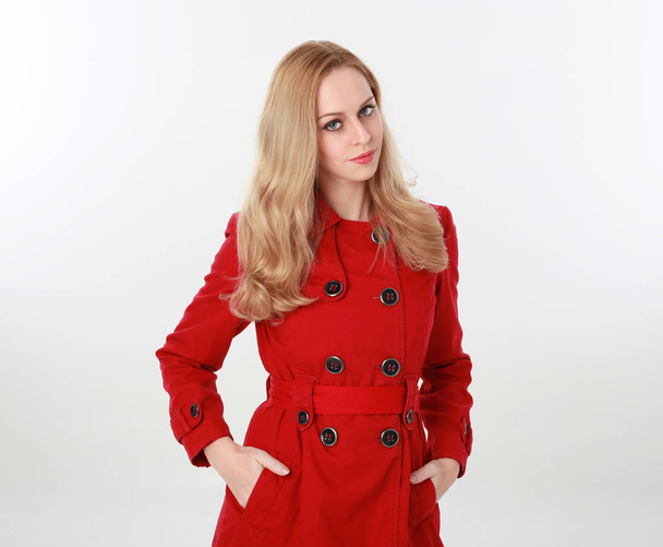 赤トレンチ コートを着てかなりブロンドの女の子の肖像画。ホワイト スタジオの背景に分離. - 写真・画像