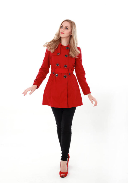 retrato de menina loira bonita vestindo casaco vermelho trincheira, comprimento total pose.. isolado no fundo do estúdio branco
. - Foto, Imagem