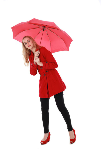 portrait of pretty blonde girl wearing red trench coat, holding an umbrella. full length standing pose. isolated on white studio background. - Фото, зображення