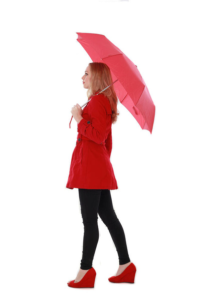 portrait of pretty blonde girl wearing red trench coat, holding an umbrella. full length standing pose. isolated on white studio background. - Fotoğraf, Görsel