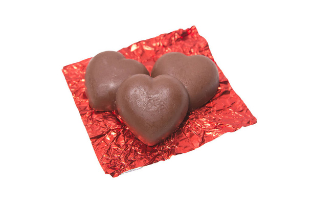 Three chocolate heart candy in red foil on white background - Фото, зображення