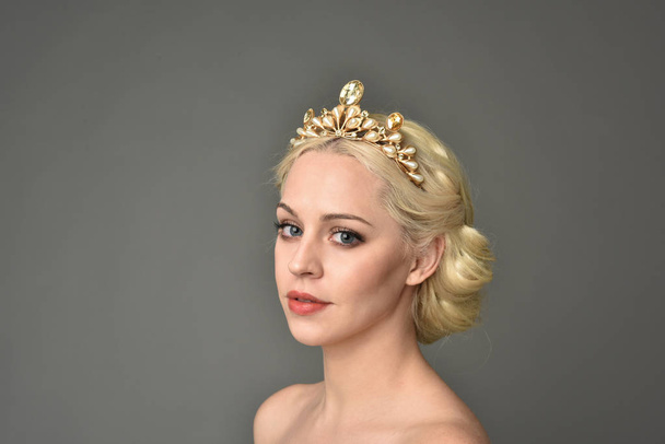portrait of blonde woman wearing golden crown, grey studio background. - Photo, Image