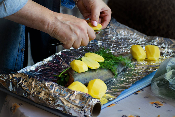 Housewife cooking salmon fish with with potatoes and and dill in foil. Tasty dish, cooked with potatoes. - Foto, Imagem