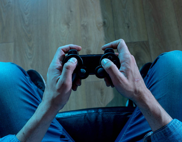 Addiction and dependency concept. close up on young man's hands with pad joystick playing video games. Male addicted to console gaming concept. - Foto, Bild