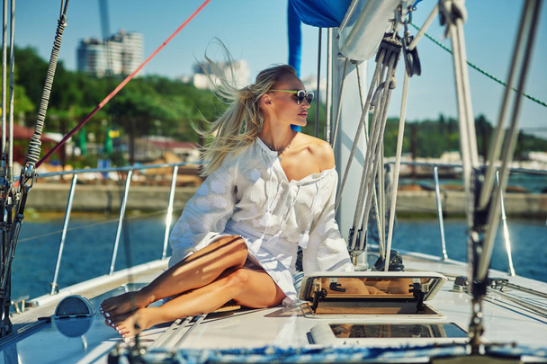 夏の日のヨットの上で魅力的な若い女性。ファッショナブルな美人の夏の屋外の船の背景に若い幸せな女。. - 写真・画像