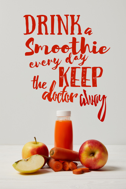Бутылка детоксикации смузи с яблоками и морковью на белой деревянной поверхности, пить смузи каждый день держать доктор от надписи
 - Фото, изображение