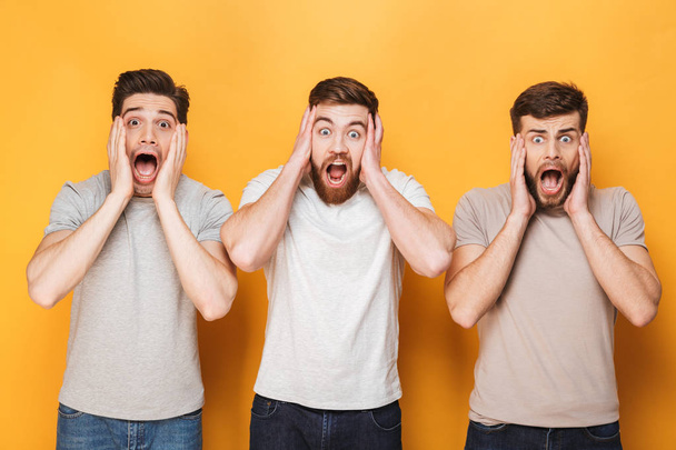 Three young shocked men screaming isolated over yellow background - Foto, Imagem