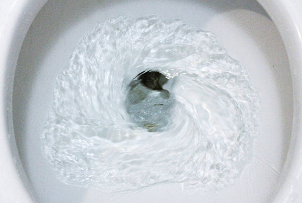 επιλεκτική εστίαση κοντά στην έξαψη λεκάνη τουαλέτας για τα υγειονομικά, τουαλέτα, έξαψη νερό, φράχω, νερό έξαψη στην τουαλέτα, μια φωτογραφία ενός λευκού κεραμικού μπολ τουαλέτας στη διαδικασία της πλύσης. Κεραμικά είδη υγιεινής για τη διόρθωση της ανάγκης με ένα - Φωτογραφία, εικόνα