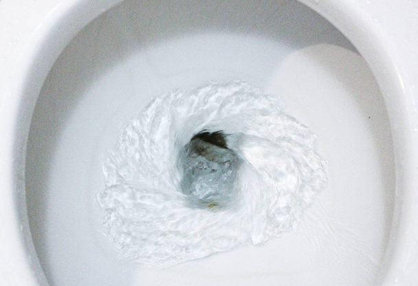 selectieve focus close-up Flushing toilet Bowl voor sanitair, toilet, blozend water, close-up, water blozen in toilet, een foto van een witte keramische toilet kom in het proces van het wassen het af. Keramische sanitair voor het corrigeren van de noodzaak met een aut - Foto, afbeelding