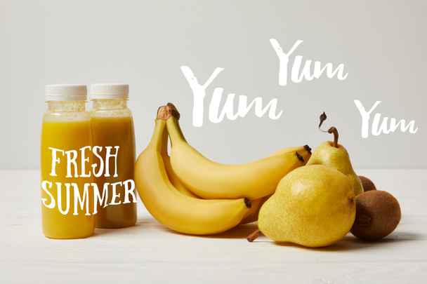 yellow detox smoothies in bottles with bananas, pears and kiwis on white background, fresh summer inscription - Фото, зображення