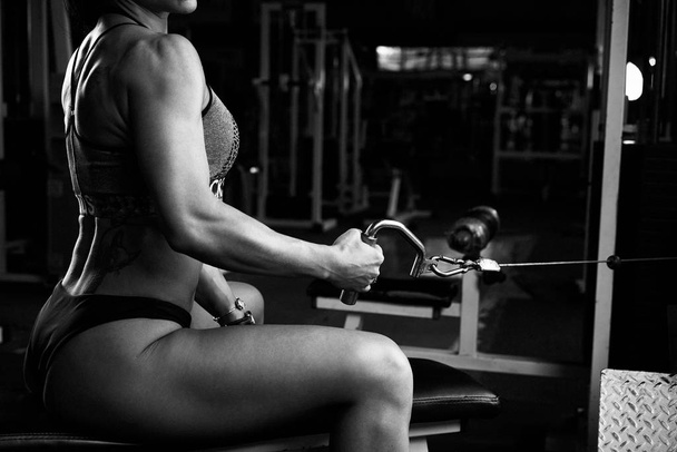 Black and white photo of young brunette muscular woman exercising in gym - Foto, imagen