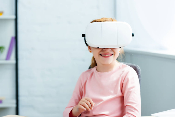 beautiful smiling redhead kid using virtual reality headset at home - Zdjęcie, obraz