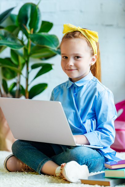 χαριτωμένο μικρό παιδί χρησιμοποιώντας φορητό υπολογιστή και να χαμογελά στη φωτογραφική μηχανή - Φωτογραφία, εικόνα