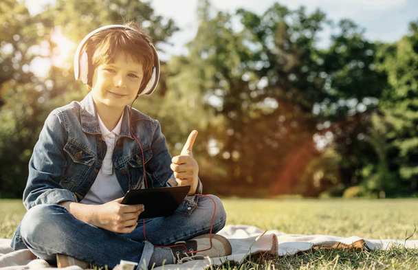 Boy with tablet and headphones showing thumb up - Fotoğraf, Görsel