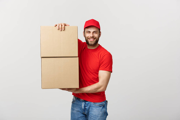 Entrega joven en uniforme rojo sosteniendo dos cajas de cartón vacías aisladas sobre fondo blanco. Copiar espacio para publicidad
 - Foto, Imagen