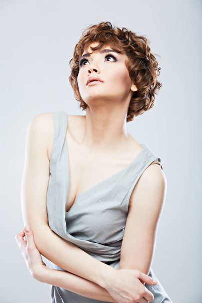 portrait of sexy young model with short curly hair wearing evening dress posing on grey background  - Foto, immagini
