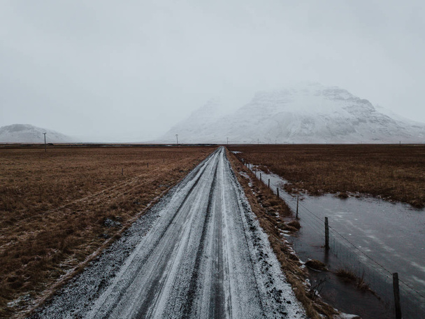 A snow covered road in Iceland, leading towards some mountains. - Foto, afbeelding