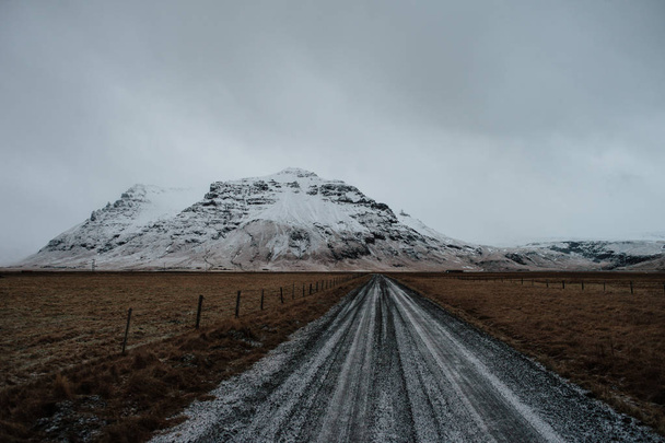 İzlanda, bazı dağlara doğru giden bir karla kaplı yolda. - Fotoğraf, Görsel