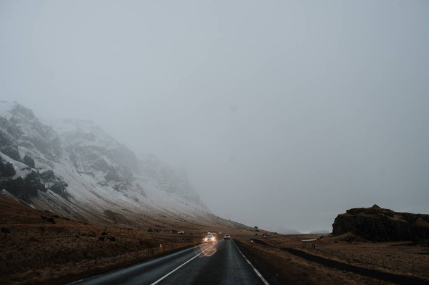 Ένας δρόμος που διέρχεται μέσα από ένα ορεινό τοπίο της Ισλανδίας με ορισμένα αυτοκίνητα οδήγηση σε αυτό - Φωτογραφία, εικόνα