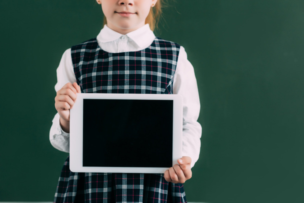 bijgesneden schot van schattige kleine schoolmeisje holding digitale tablet met leeg scherm - Foto, afbeelding