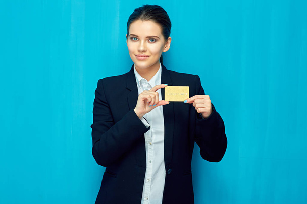 Young woman holding credit card against mouth on blue wall background - Foto, immagini