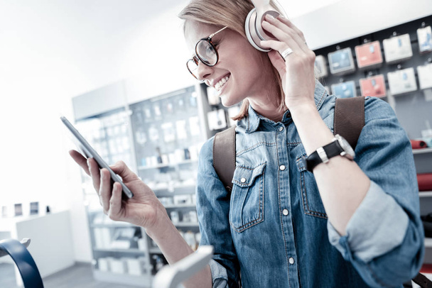 Cheerful woman looking at the screen while wearing headphones - Foto, afbeelding
