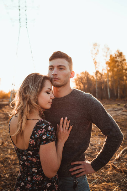 guy and girl in the field on the sunset background. - Photo, Image