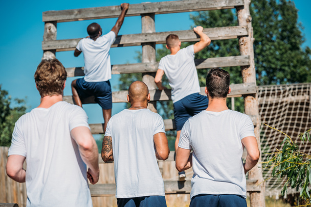 back view of multicultural soldiers practicing obstacle run on range on summer day - Fotografie, Obrázek