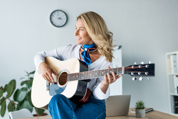 heureuse femme d'affaires attrayante jouant de la guitare acoustique au bureau
 - Photo, image