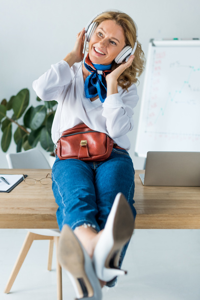 beautiful happy businesswoman listening music in headphones in office - Photo, Image